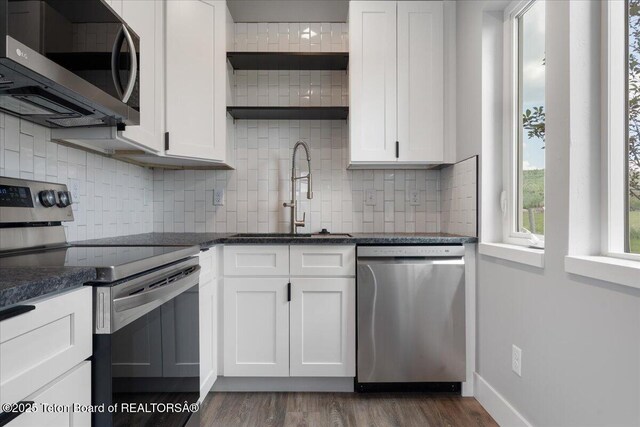 138 Larkspur Ave Unit 402, Victor, ID 83455 - kitchen featuring appliances with stainless steel finishes, open shelves, white cabinetry, decorative backsplash, and dark wood-style floors