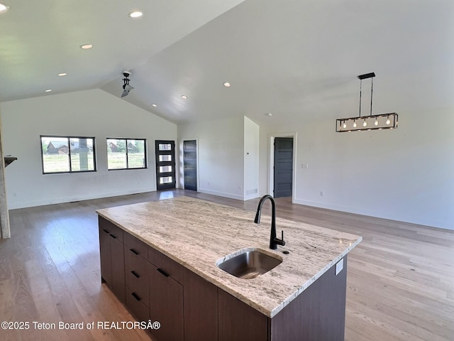 1714 River Meadows Dr, Victor, ID 83455 - kitchen featuring open floor plan, light wood-style floors, vaulted ceiling, light stone countertops, and dark brown cabinets