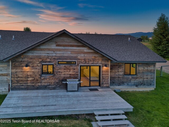 1714 River Meadows Dr, Victor, ID 83455 - back of house with a shingled roof, a wooden deck, and a lawn