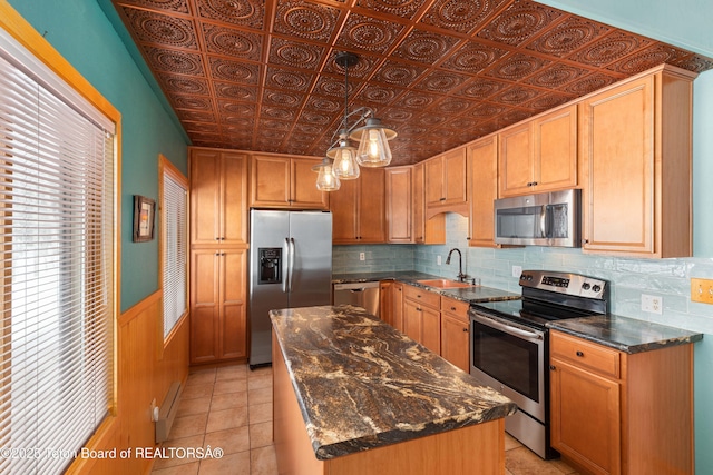 kitchen featuring an ornate ceiling, a sink, stainless steel appliances, backsplash, and a center island