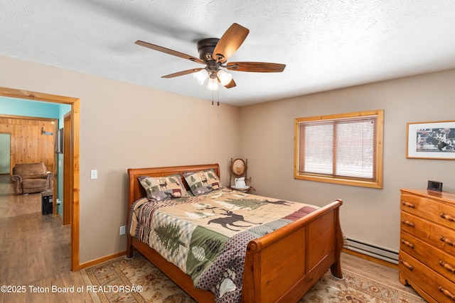 bedroom with a ceiling fan, baseboards, a baseboard radiator, a textured ceiling, and light wood-type flooring