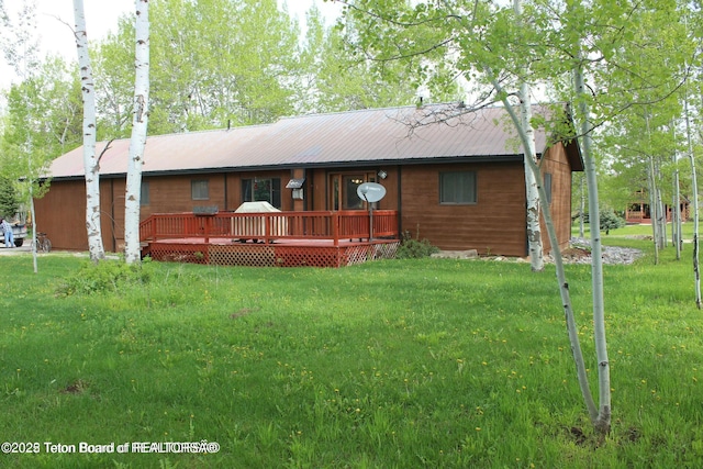 view of front of home featuring a front lawn, metal roof, and a wooden deck
