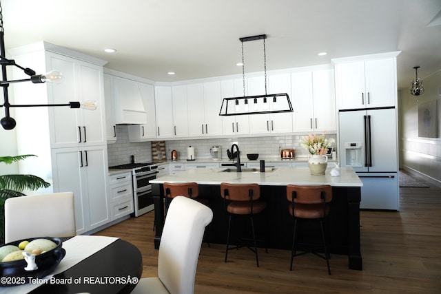 825 Mccoy Dr, Pinedale, WY 82941 - kitchen with white cabinets, high end fridge, a sink, range with two ovens, and custom range hood