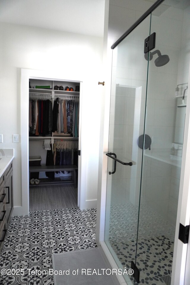 825 Mccoy Dr, Pinedale, WY 82941 - bathroom featuring tile patterned floors, vanity, a walk in closet, and a stall shower