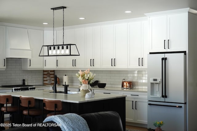 825 Mccoy Dr, Pinedale, WY 82941 - kitchen with a sink, white cabinetry, a breakfast bar area, white fridge with ice dispenser, and premium range hood