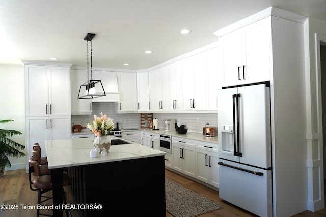 825 Mccoy Dr, Pinedale, WY 82941 - kitchen featuring decorative backsplash, a kitchen bar, white fridge with ice dispenser, pendant lighting, and a center island