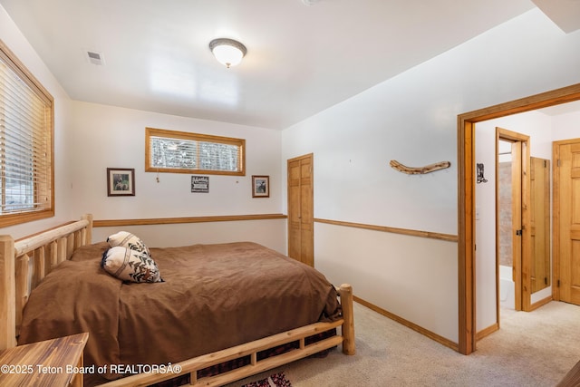 bedroom with baseboards, visible vents, and light colored carpet