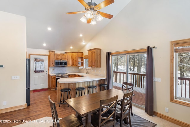 dining area featuring baseboards, high vaulted ceiling, ceiling fan, and a healthy amount of sunlight