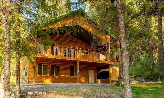 rear view of house featuring faux log siding and a wooden deck