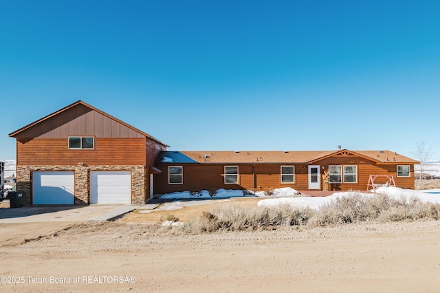 view of front of property with an attached garage, stone siding, and concrete driveway