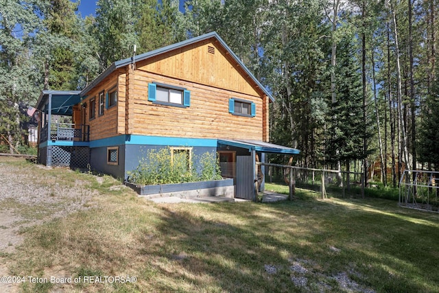back of house featuring log siding and a yard