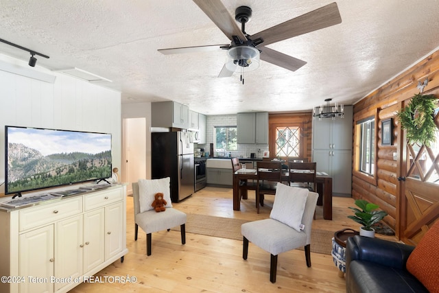 living area featuring ceiling fan, light wood-style floors, rustic walls, and a textured ceiling