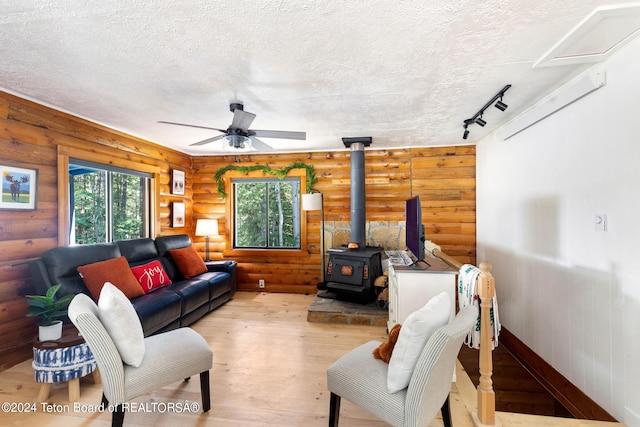 living room with light wood-style flooring, log walls, a wood stove, and a textured ceiling
