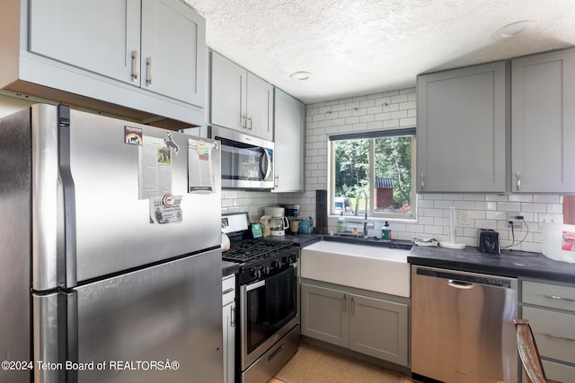 kitchen featuring a sink, dark countertops, appliances with stainless steel finishes, and gray cabinetry