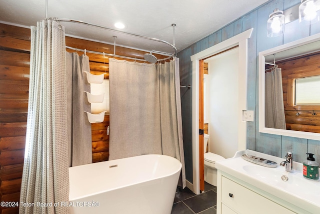 full bath featuring vanity, wood walls, toilet, tile patterned floors, and a freestanding bath