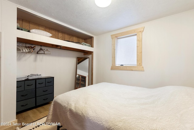 bedroom with a textured ceiling and wood finished floors