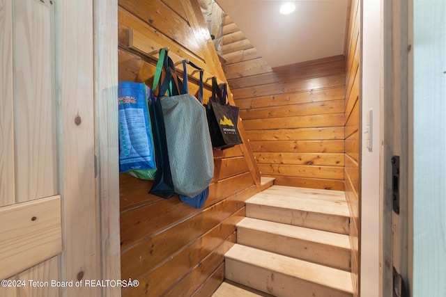 staircase featuring wood walls