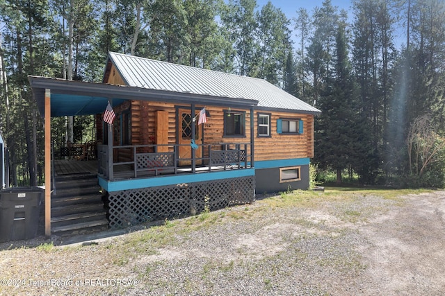 view of front facade featuring log exterior, a porch, and metal roof