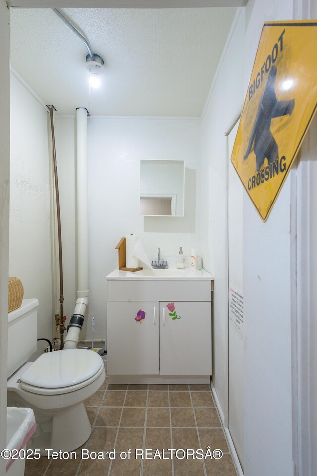bathroom featuring toilet, tile patterned flooring, vanity, and a textured ceiling