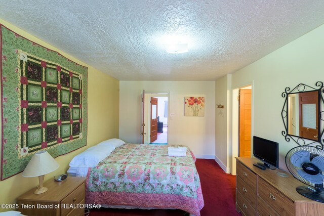 bedroom with baseboards, a textured ceiling, and dark carpet