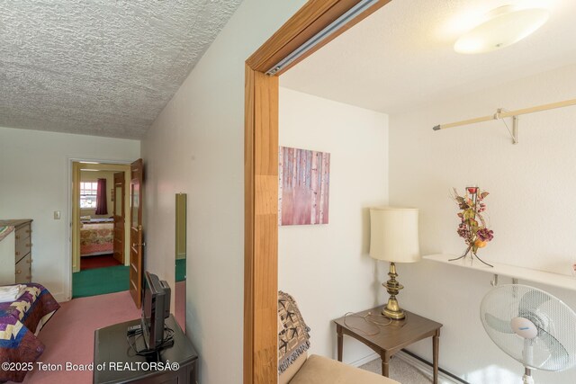 corridor with carpet floors and a textured ceiling