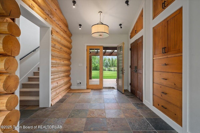 3300 N Trapper Ln, Wilson, WY 83014 - entrance foyer featuring stone tile flooring, rustic walls, and stairway