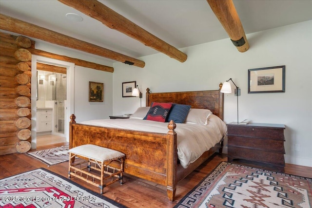 3300 N Trapper Ln, Wilson, WY 83014 - bedroom featuring rustic walls, wood finished floors, beamed ceiling, and connected bathroom