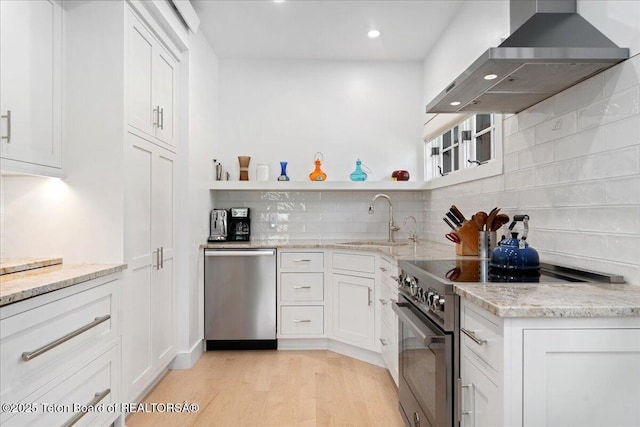 3300 N Trapper Ln, Wilson, WY 83014 - kitchen featuring wall chimney range hood, appliances with stainless steel finishes, light wood-type flooring, open shelves, and white cabinets