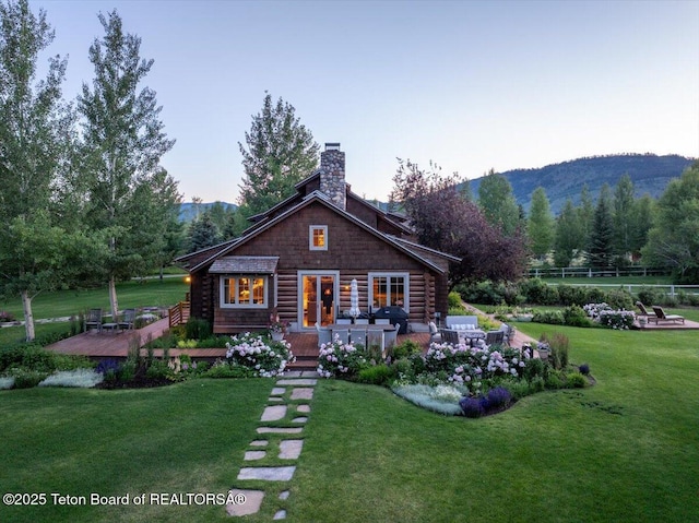 3300 N Trapper Ln, Wilson, WY 83014 - view of front of house featuring a front yard, a chimney, a mountain view, and log exterior