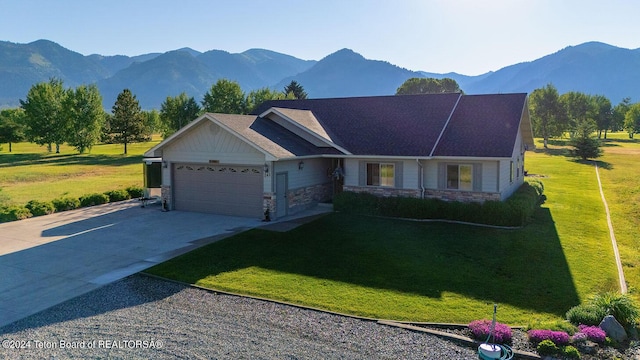 view of front facade featuring a mountain view, stone siding, a garage, a front lawn, and driveway