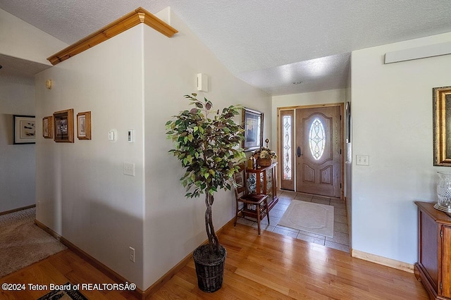 entrance foyer with baseboards, light wood finished floors, and a textured ceiling