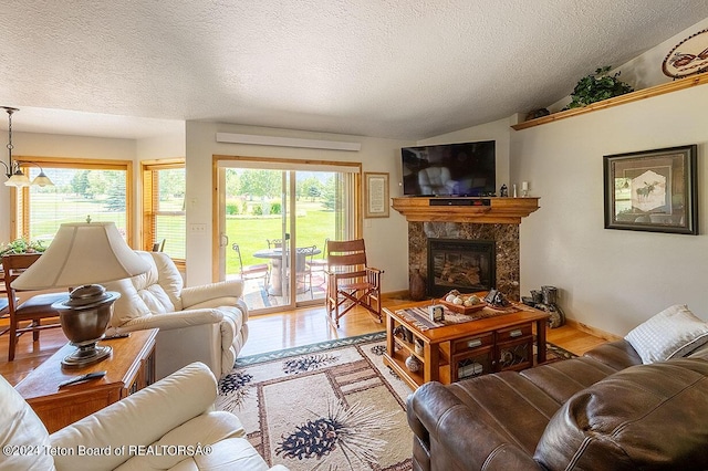 living area with a textured ceiling, a premium fireplace, vaulted ceiling, and wood finished floors