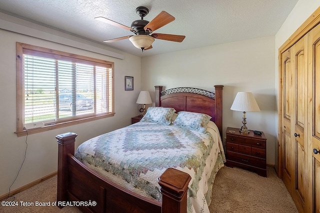 bedroom with baseboards, a ceiling fan, light carpet, and a textured ceiling