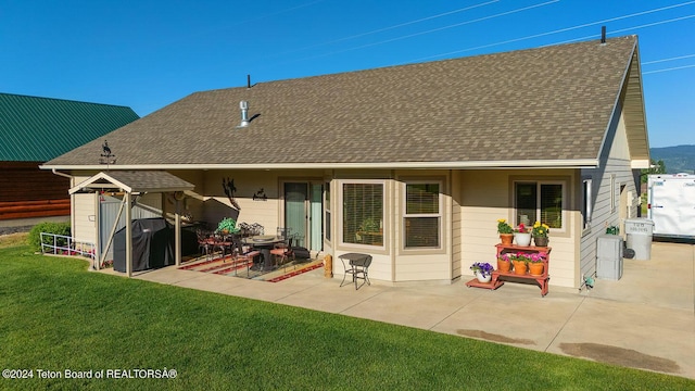 back of house with a patio, a yard, and a shingled roof