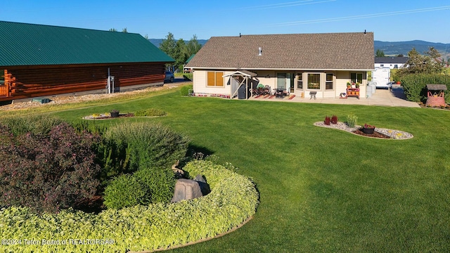 rear view of house featuring a patio, a yard, log exterior, and a mountain view