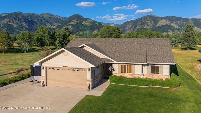 ranch-style home with a front yard, a mountain view, stone siding, a garage, and driveway