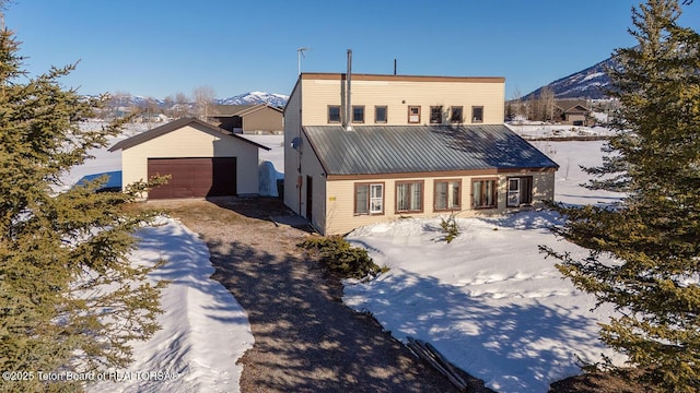 view of front facade featuring a mountain view, metal roof, a detached garage, and an outdoor structure
