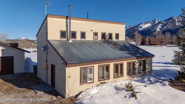 snow covered rear of property featuring metal roof and a mountain view