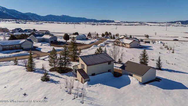 snowy aerial view with a mountain view and a residential view