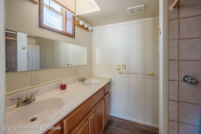 bathroom featuring a sink, visible vents, baseboards, and double vanity
