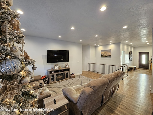 living area featuring recessed lighting, baseboards, a textured ceiling, and wood finished floors