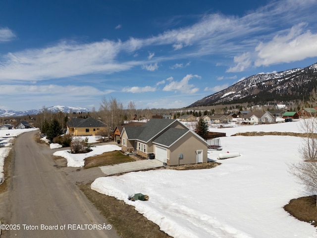 snowy aerial view featuring a mountain view and a residential view