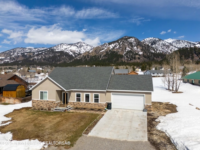 view of front of property featuring a garage, stucco siding, stone siding, a mountain view, and driveway