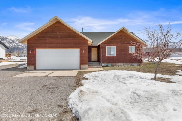 view of front facade with a garage, a mountain view, and driveway
