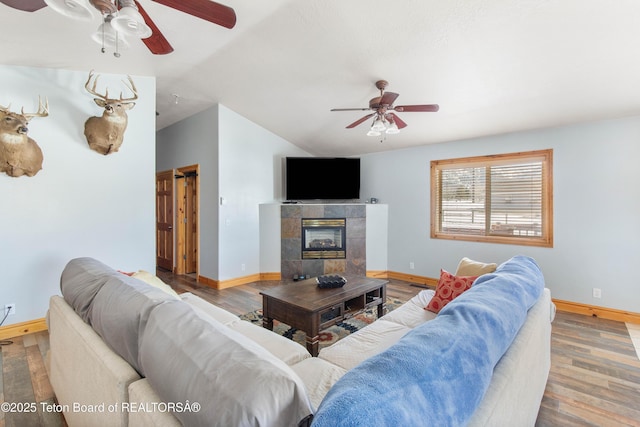 living room featuring a ceiling fan, baseboards, wood finished floors, and lofted ceiling
