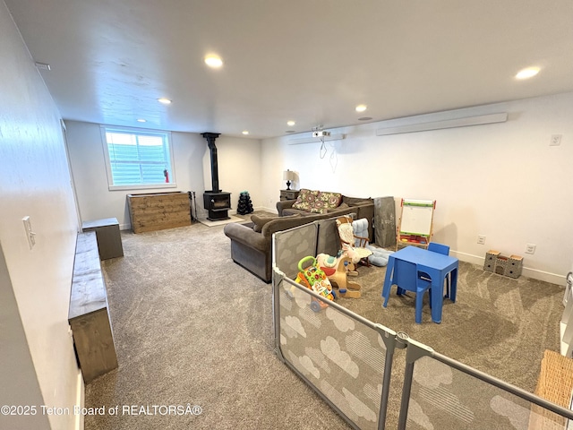 carpeted living area featuring a wood stove, baseboards, and recessed lighting