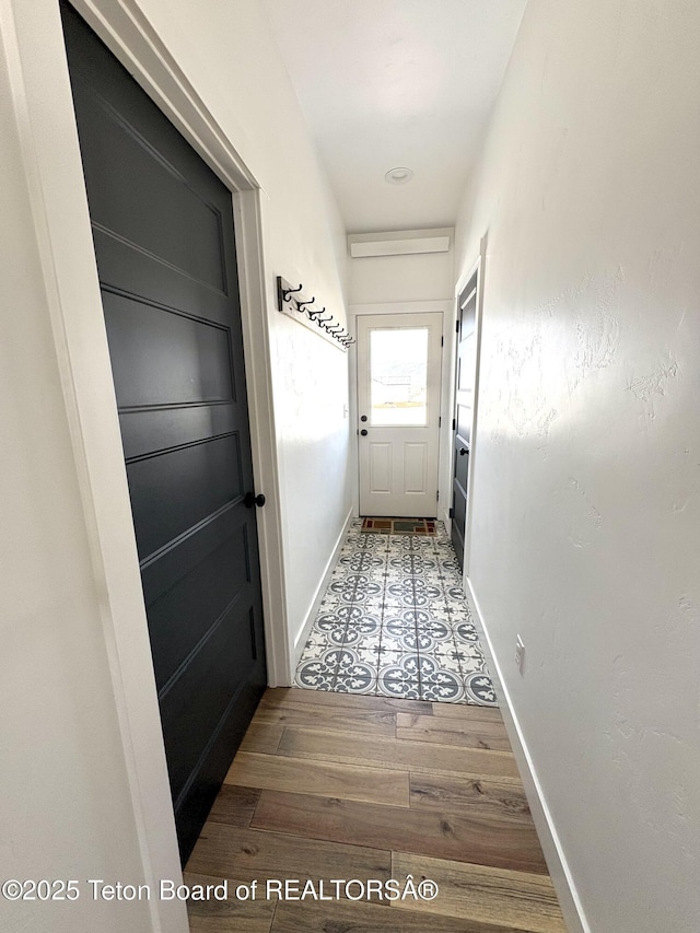 doorway to outside with wood finished floors and baseboards