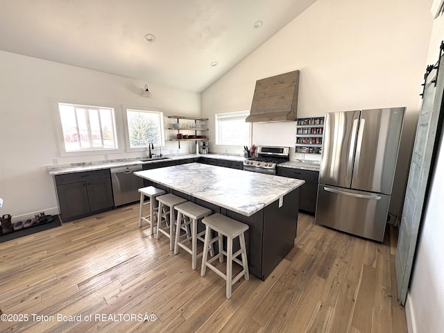 kitchen with a breakfast bar, premium range hood, open shelves, stainless steel appliances, and a sink