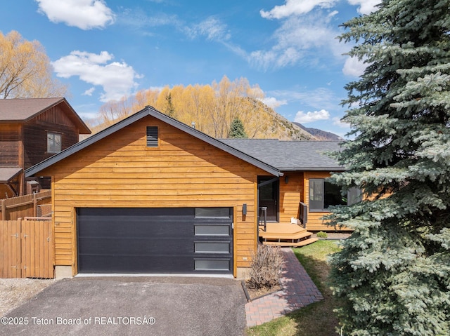 2032 Dandelion Ct, Jackson, WY 83001 - view of front of house with asphalt driveway, an attached garage, fence, and a deck with mountain view