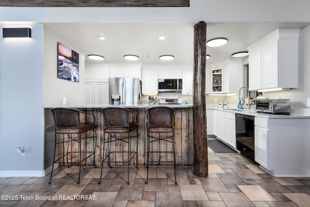 17 C B Ln, Pinedale, WY 82941 - kitchen with appliances with stainless steel finishes, a kitchen bar, stone finish flooring, white cabinets, and recessed lighting